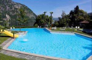 a large swimming pool with a mountain in the background at Apartment Bella Vista Lugano in Bissone