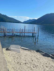 a dock on a body of water with mountains at Apartment Bella Vista Lugano in Bissone
