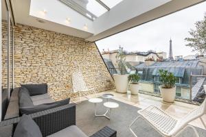 een balkon met een bank en stoelen en een bakstenen muur bij Sweet Inn - Boccador in Parijs