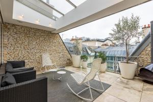 a patio with chairs and a couch on a balcony at Sweet Inn - Boccador in Paris