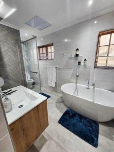 Baño blanco con bañera y lavamanos en Margate Manor en Pretoria