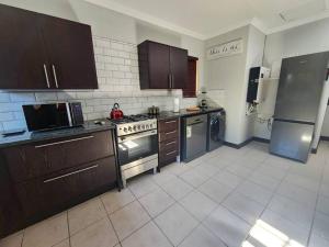 uma cozinha com electrodomésticos de aço inoxidável e armários castanhos em Margate Manor em Pretoria