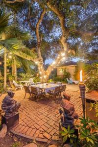 a patio with a table and a tree with lights at Bohemian Art & Garden Cottage Santa Barbara in Santa Barbara