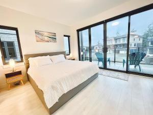 una camera da letto con un letto grande e grandi finestre di Ocean View Town House #4 at THE BEACH HOUSE! a Campbell River