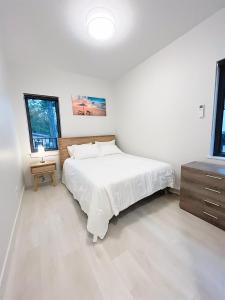 a white bedroom with a bed and a dresser at Ocean View Town House #4 at THE BEACH HOUSE! in Campbell River