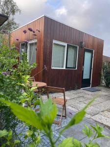 uma pequena casa de madeira com uma mesa e um banco em Bed & Breakfast Danina em Sassenheim