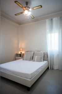 um quarto com uma cama branca e uma ventoinha de tecto em Villa Aphrodite em Paleros