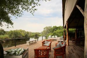 una terraza de madera con sillas y un sofá. en Zambezi Dusk, en Livingstone