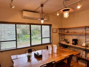 a dining room with a wooden table and two windows at Yakushima Minsyuku Suginoko in Yakushima