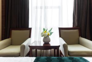 um quarto com duas cadeiras e um vaso de flores sobre uma mesa em Shenzhen Shangyuan International Hotel Longhua Metro em Shenzhen