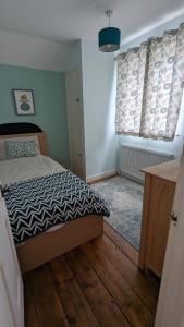 a bedroom with a bed and two windows with curtains at Cosy family cottage south Somerset in Long Sutton