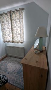 a lamp on top of a wooden table in a room at Cosy family cottage south Somerset in Long Sutton