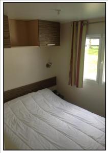 a bedroom with a white bed with a window at Camping Happy Pyrénées in Saligos