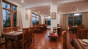 a restaurant with wooden tables and chairs and windows at Hotel Youthok Heritage in Leh