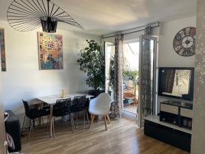 Un comedor con una mesa y sillas y un reloj. en COSY STUDIO PARIS LA DÉFENSE, en Courbevoie