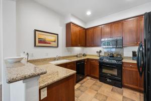 a kitchen with wooden cabinets and a black refrigerator at C77-1 Lux 1BD Villa near Clubhouse with all amenities condo in La Quinta