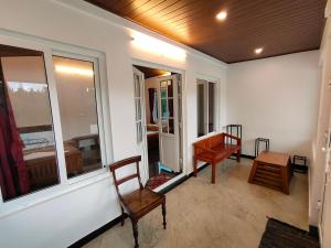 a room with two chairs and a table and windows at Silver Spruce Glass Villa 1BHK Kotagiri in Kotagiri