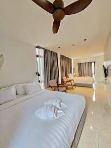 a bedroom with a large white bed with a ceiling fan at Calamint Residence Hotel ( คาลามิ้นท์) in Chumphon