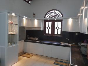 een keuken met witte kasten, een raam en een wastafel bij JANA HOUSE in Galle