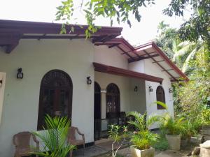 una casa blanca con dos puertas y algunas plantas en JANA HOUSE en Galle