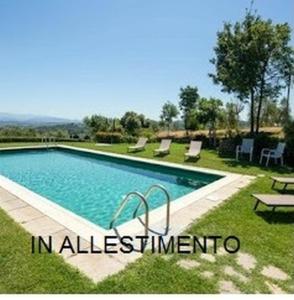 a swimming pool with chairs and a table in the grass at Cascina del Poeta in Recanati