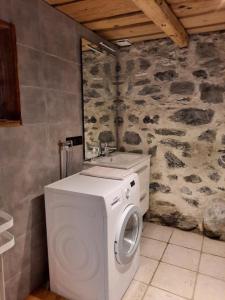 a white washing machine in a bathroom with a stone wall at Chalet la corne du chamois in Sixt