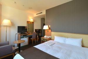 弘前市にあるブロッサムホテル弘前のベッドとデスクが備わるホテルルームです。
