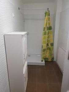 La salle de bains est pourvue d'un réfrigérateur blanc et d'un rideau de douche jaune. dans l'établissement Kontyos Vendégház, à Felsőtold
