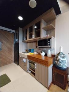 a kitchen with wooden cabinets and a sink and a microwave at Apartemen Uttara the Icon in Yogyakarta