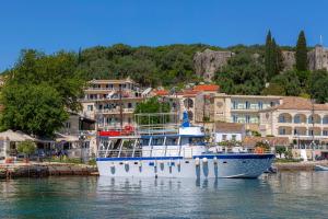 a boat is docked in the water near a town at Solaris Methea Deluxe Suites in Kassiopi