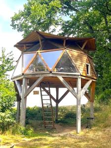 une grande structure en bois avec une échelle dans l'herbe dans l'établissement Domaine du Balbuzard, à Condat-en-Combraille