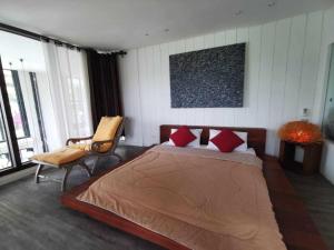 um quarto com uma cama grande e uma cadeira em Baantidnam em Ban Thung Tho