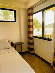 a bedroom with a bed and a window with a view at Villa Malinao Oceanview Resort- Superior Bungalow in Burgos