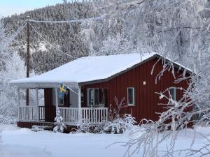Una cabaña roja con nieve encima. en Villa Stuga, en Hammarstrand