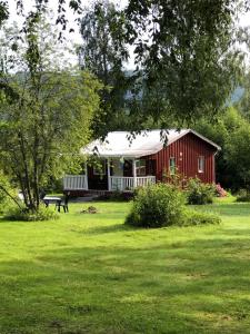 een rode schuur met een picknicktafel in een tuin bij Villa Stuga in Hammarstrand