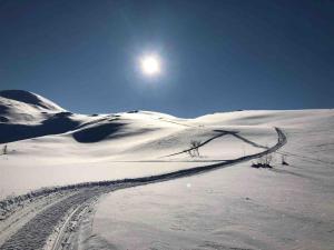 a snow covered hill with a fence in the snow at Kleiva 8 Skorovas in Namsskogan