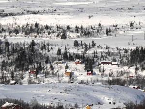a snow covered mountain with houses and trees at Kleiva 8 Skorovas in Namsskogan