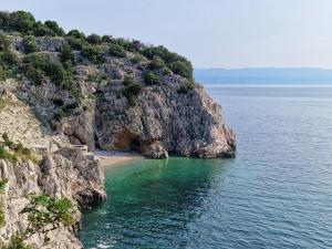 a beach on the side of a rocky cliff at Guesthouse Villa Galovic in Brseč