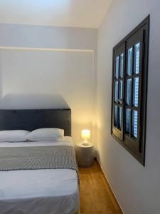 a bedroom with a bed with a lamp and a window at The Blue Lagoon Apartment in Aliki