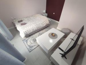 Cette petite chambre blanche comprend un lit et une table. dans l'établissement Apartman Matej, à Trebinje