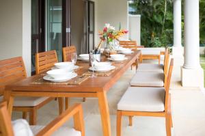 drewniany stół z krzesłami, płytkami i kwiatami w obiekcie Eden Island Luxury Ocean Front Villa with Pool w Victorii