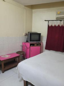 1 dormitorio con 1 cama, TV y mesa en JAI MALHAR LODGE, en Pune