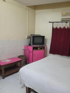 1 dormitorio con 1 cama, TV y mesa en JAI MALHAR LODGE en Pune