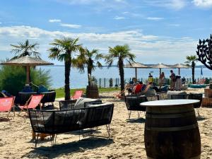 a beach with chairs and tables and palm trees at FeWo Traumblick - Himmel & Meer mit TRAUM Meerblick am Strand mit großem Balkon - WLAN, Streaming, 2024 modernisiert in Sierksdorf