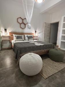 1 dormitorio con 1 cama grande y 2 reposapiés en L'oiseau vert apartments, en Rodrigues Island