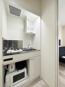 a white kitchen with a sink and a microwave at bHOTEL Yutori - Nice Apt in Onomichi near the Station for 3Ppl in Onomichi