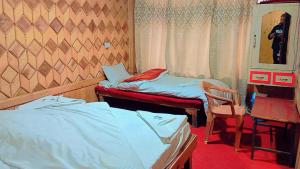 Habitación con 2 camas, mesa y silla en Hotel Mehak And Restarunt, en Pahalgām