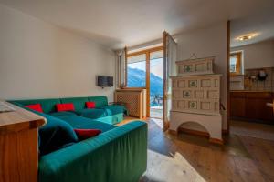 sala de estar con sofá verde y chimenea en Cesa Azola, en Vigo di Fassa