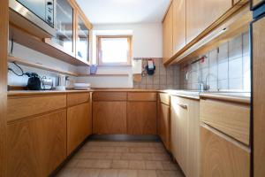 una pequeña cocina con armarios de madera y una ventana en Cesa Azola, en Vigo di Fassa