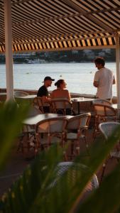 um grupo de pessoas sentadas em mesas na praia em Hotel Glavovic em Lopud